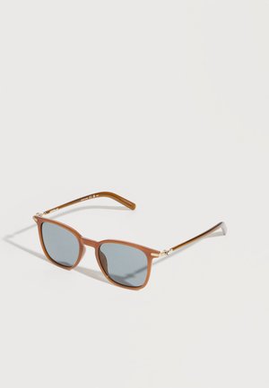 Slnečné okuliare s hnedým rámom, obdĺžnikovými sivými šošovkami a tenkými zlatými stranicami na jednoduchom svetlom pozadí.