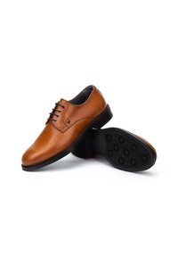 Chaussures de ville en cuir marron avec une finition lisse, bout rond et système de laçage. La semelle en caoutchouc noir présente des motifs de grip circulaires.