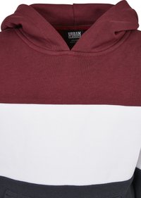 Felpa con cappuccio con una parte superiore color bordeaux, una banda centrale bianca e una parte inferiore grigio scuro. Realizzata in tessuto morbido con dettagli di cucitura visibili.