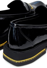 Chaussures en cuir verni noir avec une semelle épaisse noire et des coutures d'accent jaune. Présentent un orteil arrondi et des détails de couture subtils.