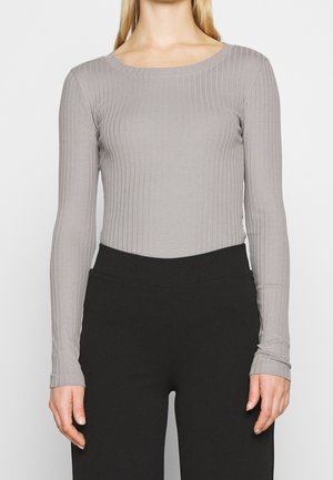 Long-sleeve ribbed top in light gray fabric with a rounded neckline, paired with black fitted pants. Smooth texture and form-fitting design.