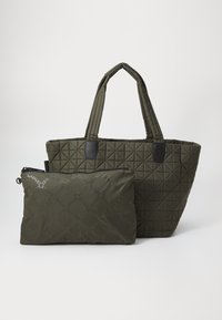 Quiltet grønn toteveske med to håndtak, med svarte detaljer. Inkluderer en matchende glidelåspose med et repeterende logomønster.