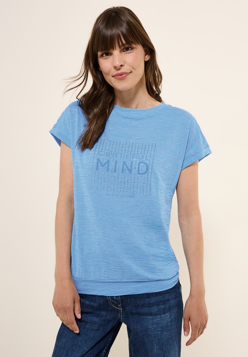 T-shirt bleu clair à manches courtes avec une finition texturée. Le graphique central indique "ESPRIT RECONNAISSANT" avec un motif de points. Coupe décontractée.