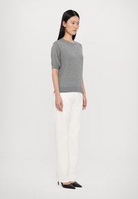 Grå kortermet genser med rund hals, kombinert med hvite høy midje bukser og svarte spisse hæler.