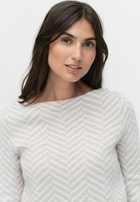 Pull léger gris clair avec un motif en chevrons, présentant un col bateau et des manches longues, fabriqué en tissu doux au toucher lisse.
