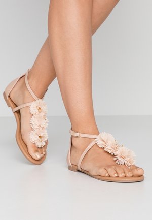 Jasnoróżowe sandały z kwiatowymi akcentami, z płaską podeszwą i regulowanym zapięciem w kostce. Wykonane z miękkiego materiału, ozdobione detalami na palcach.