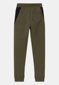 Olive zelené sportovní kalhoty vyrobené z jemné bavlny, s černými postranními panely, zadní kapsou a elastickými manžetami a pasem.