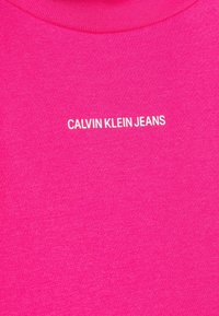 Felroze T-shirt met een ronde hals, voorzien van de tekst "CALVIN KLEIN JEANS" in het wit, met een gladde textuur en een aansluitend ontwerp.