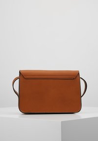 Brun väska i konstläder med rektangulär form, plan flikstängning och dubbla handtag, med rena linjer och minimala detaljer.