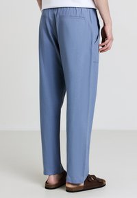 Helleblaue Hosen aus weichem Stoff, mit einem elastischen Bund, Seitentasche und geradem Bein.