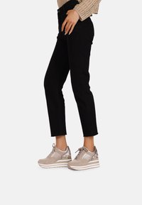 Sneaker beige con tomaia in mesh e suede, con un accento metallico e una suola piatta bianca. Indossate con jeans neri a vita alta.