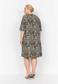 Tiermusterkleid mit weitem Schnitt, kurzen Ärmeln und knielangem Design in Creme mit braunen und schwarzen Leopardenflecken.