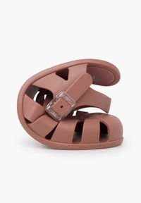 Brown molded rubber sandal with an open-toe design, featuring cutouts and a transparent adjustable strap for secure fit.
