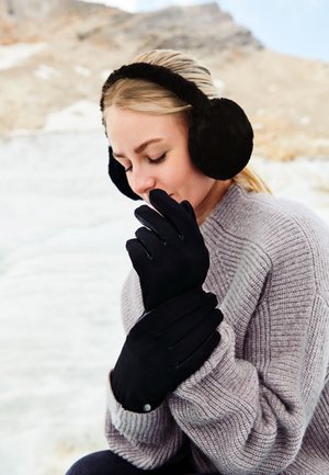 Black gloves with smooth texture and fitted design, paired with black fur earmuffs. The background features a snowy terrain and mountains.