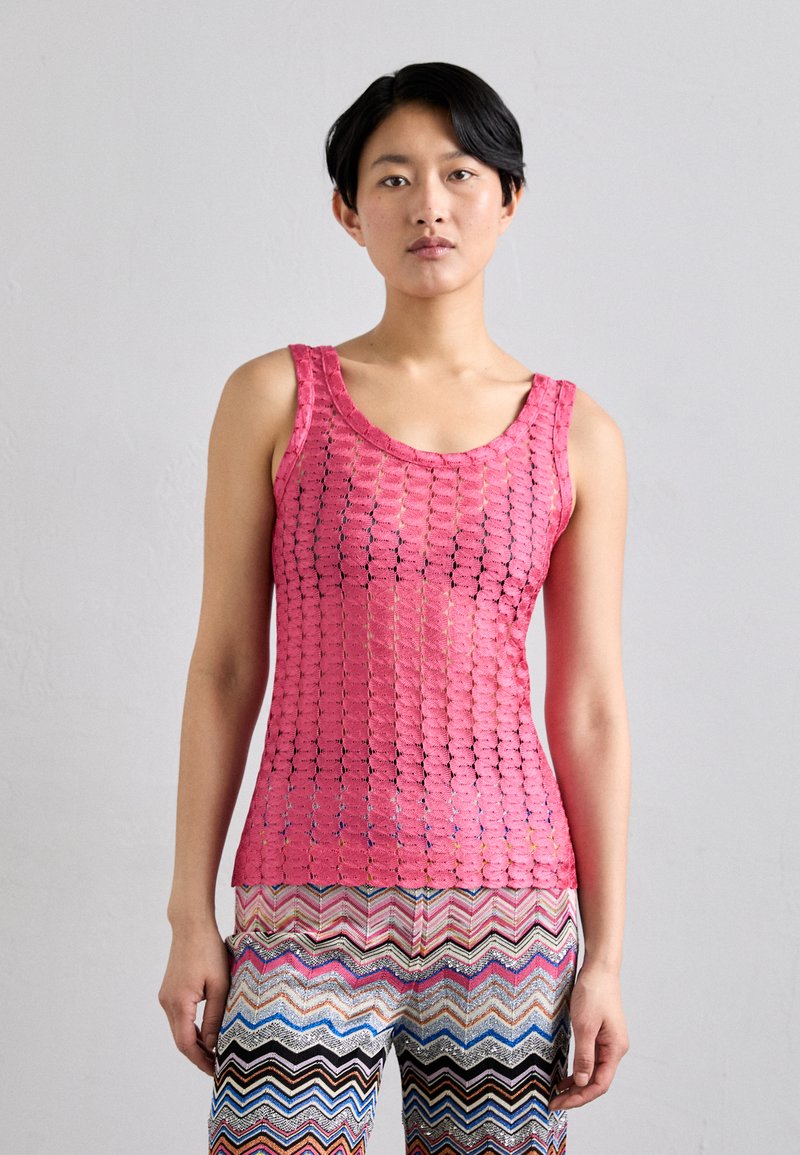 Rózsaszín horgolt tank top, kör alakú, nyitott kötésű dizájnnal, széles vállpántokkal, zig-zag mintás, multicolor nadrággal párosítva.
