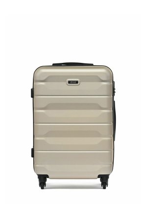 Beżowa walizka z twardą powłoką, posiadająca cztery czarne kółka, górny uchwyt oraz poziome rowki na powierzchni.