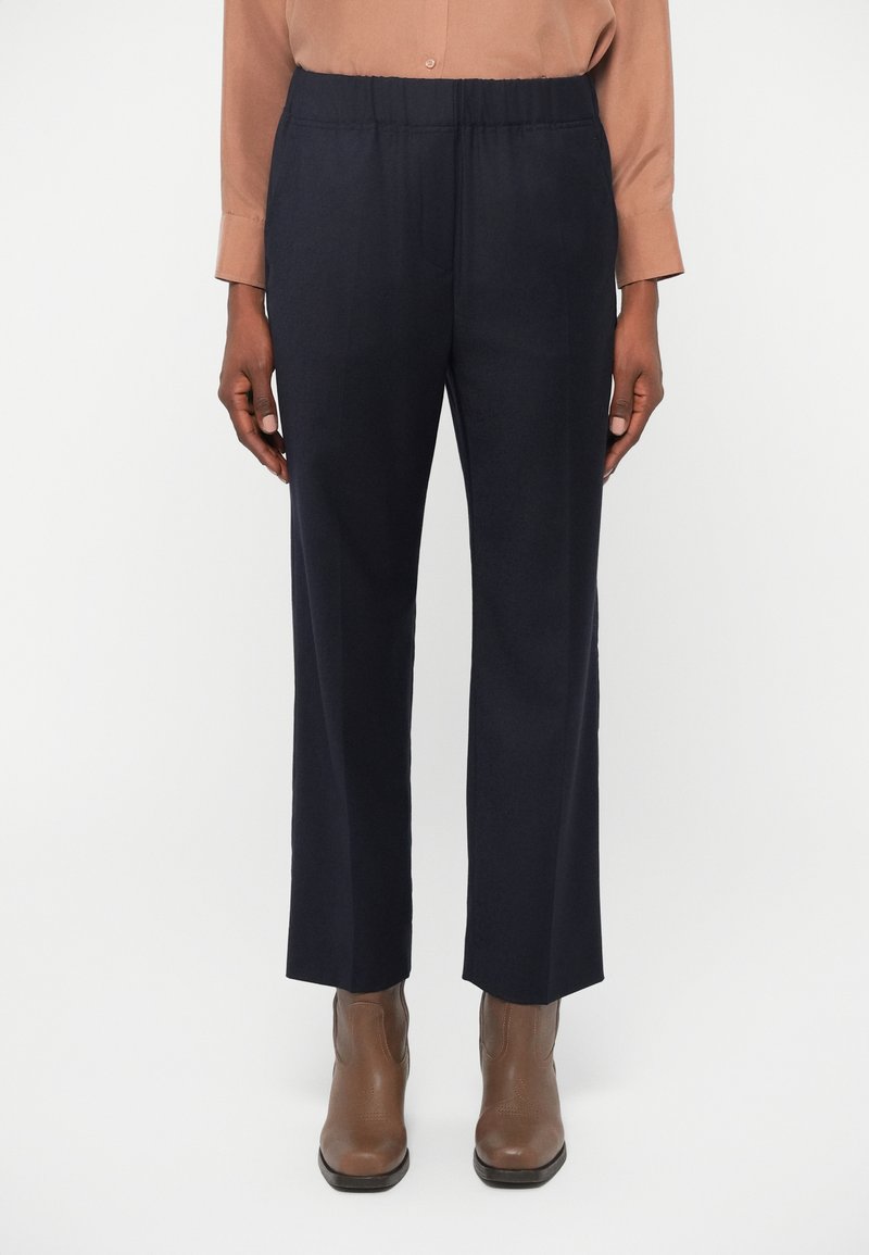 Navy trousers with an elastic waistband, straight leg design, and a smooth texture. Pairing with brown ankle boots.