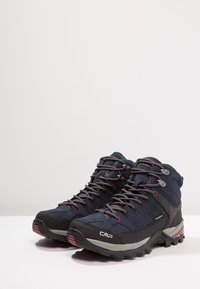 Marineblaue Wanderschuhe mit strukturiertem Obermaterial, grauen Akzenten und roten Schnürsenkeln. Sie verfügen über eine robuste schwarze Sohle und ein wasserdichtes Design für den Einsatz im Freien.