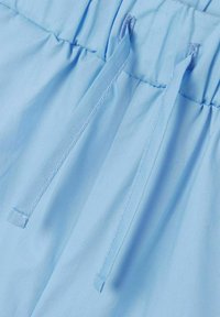 Lichtblauwe stof met een elastische tailleband en trekkoord. Soepele textuur met subtiele plooien en twee verticale stiksels.