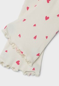 Weiße Knöchelsocken mit einem kleinen rosa Herzmuster und einem Rüschensaum am Bund, aus einem weichen, dehnbaren Material gefertigt.