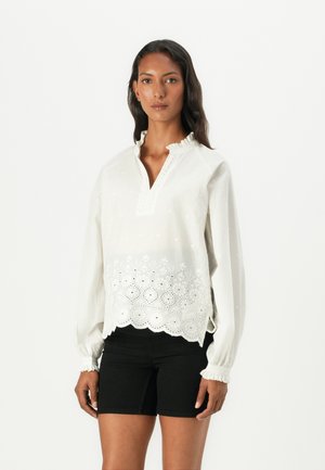 Hvit brodert bluse med bølget kant, med detaljerte blomstermønstre, v-hals med rynket krage og elastiske ermer.