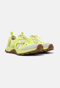 Scarpe da ginnastica giallo luminoso con suola testurizzata, dotate di un sistema di cinturini regolabili e di un rivestimento morbido per il comfort.