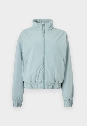 Veste bleu clair zippée avec col montant, poignets élastiques et taille élastique, présentée sur un fond blanc.