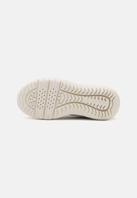 Soletta di sneaker in gomma crema chiaro con un motivo di grip testurizzato, dotata di perforazioni per la traspirabilità e dettaglio del logo del brand.