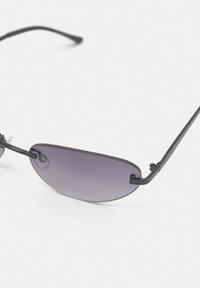 Sunglasses med mörklila, ovala linser och en tunn svart metallram. Har justerbara näsbud och stiliga, smala tempel.