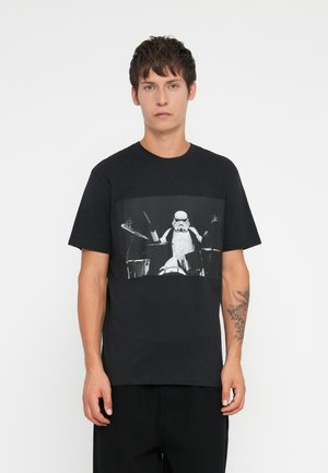 Black cotton t-shirt featuring a graphic of a Stormtrooper playing drums in black and white. Crew neckline, short sleeves, relaxed fit.