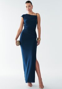 Tmavě modré večerní šaty s nabíraným živůtkem, bočním rozparkem a nastavitelnými tenkými ramínky. Hladká textura, přiléhavý střih a minimální zdobení.