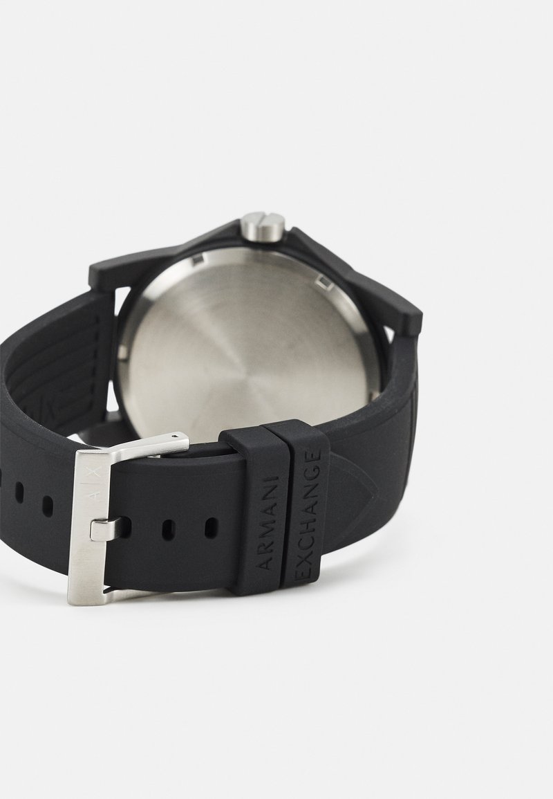Pulsera de reloj de silicona negra con hebilla de acero inoxidable. Acabado mate en la pulsera, con marca grabada y acentos texturizados detallados. Caja metálica redonda.