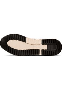 Shoe sole with a thick black rubber base featuring horizontal and vertical ridges, contrasted by a lighter beige section in the center.