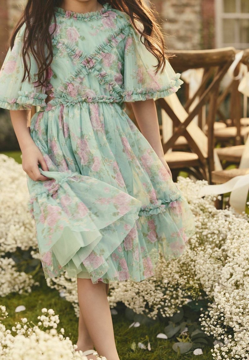 Robe florale vert menthe avec des manches à volants et une jupe en tulle à étages. Présente des motifs de fleurs roses et un détail de taille élastique.