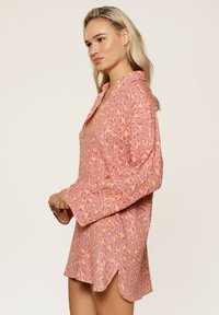 Roze en oranje luipaardprint jurk met een kraag, lange mouwen en zijsplitten. Gemaakt van zachte stof met een relaxte pasvorm.