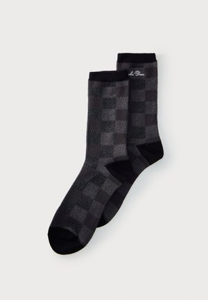 Par de calcetines a cuadros en gris oscuro y negro con dedos, talones y puños negros, y un pequeño texto blanco bordado cerca de la parte superior.