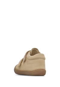Zapatos para niños pequeños en ante color tostado con diseño de tobillo bajo, correa de velcro y suela de goma texturada. Presenta un branding minimalista en el lateral.