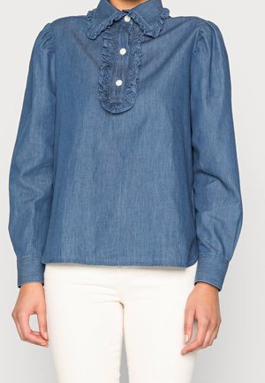 Denimbluse med rynket krave og stolpe, lange ærmer og en afslappet pasform. Lyseblå farve med subtil struktur. Knaplukninger.