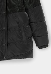 Czarna kurtka puchowa z teksturowaną górną częścią, zatrzaskami, kieszeniami podszewkowymi z polaru oraz ściągaczami przy mankietach dla pewnego dopasowania.