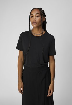 T-shirt nera a maniche corte con scollatura a girocollo, realizzata in un tessuto morbido, abbinata a una gonna nera con un design semplice.