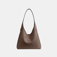 Sac à bandoulière en cuir marron avec une seule sangle et un petit bouton doré sur la poche avant, sur un fond clair uni.