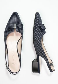 Zapatos slingback azul marino con lunares blancos, punta afilada, pequeño lazo decorativo y tacón cuadrado. Tela suave con una plantilla lisa.