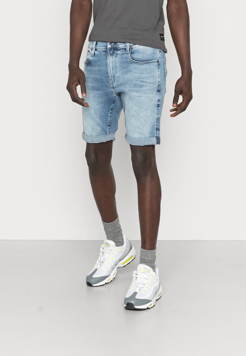 Jeansshorts i ljusblått med en urtvättad effekt, med uppvikta fållar, femficksdesign och knappgylf. Matchas med grå strumpor och sneakers.