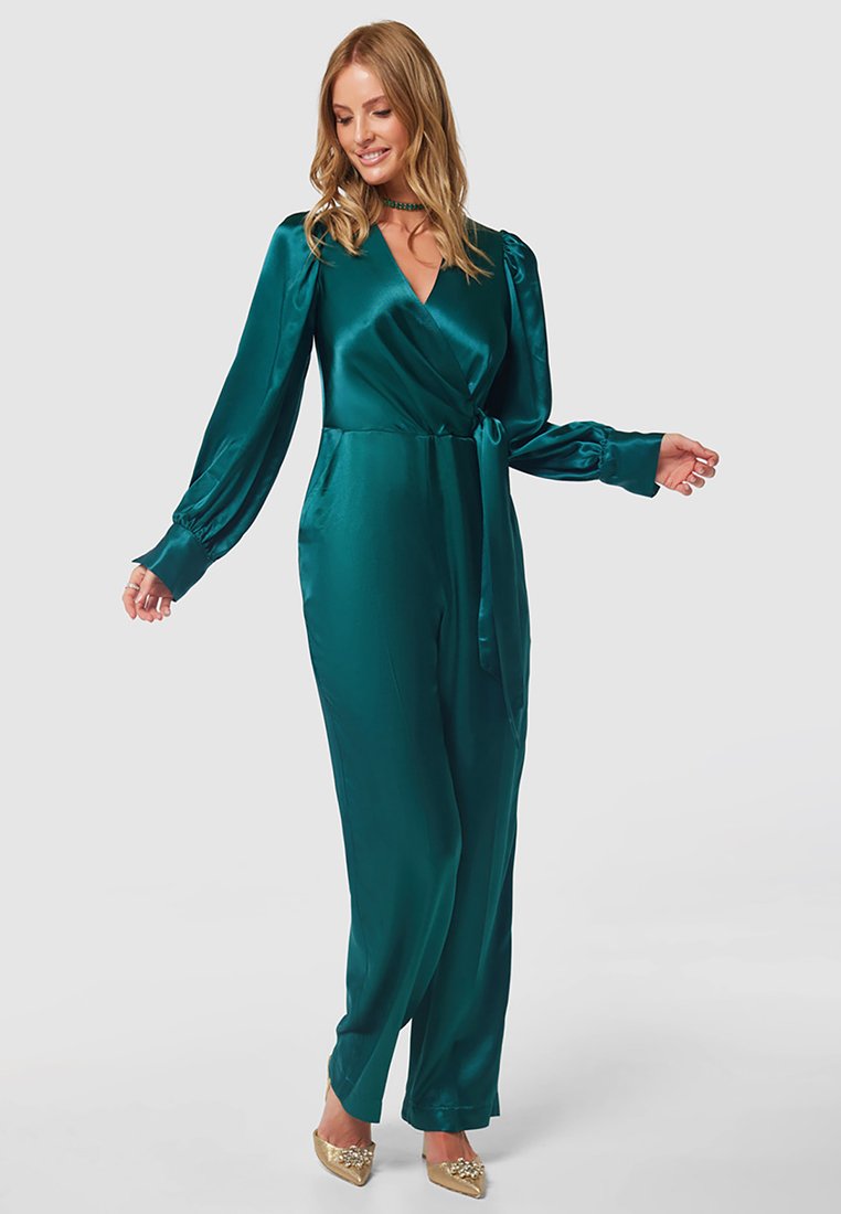 Türkiser Satin-Jumpsuit mit langen Ärmeln, Wickeldesign und gebundenem Taillenbund. Er hat eine glatte Textur und leicht locker sitzende, schmal zulaufende Beine.