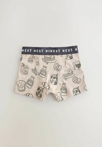 Boxer beige avec une ceinture noire répétant « NEXT », imprimé de dessins au trait noirs représentant des aliments pour le petit-déjeuner comme des toasts, des briques de lait, des pancakes et des bretzels.