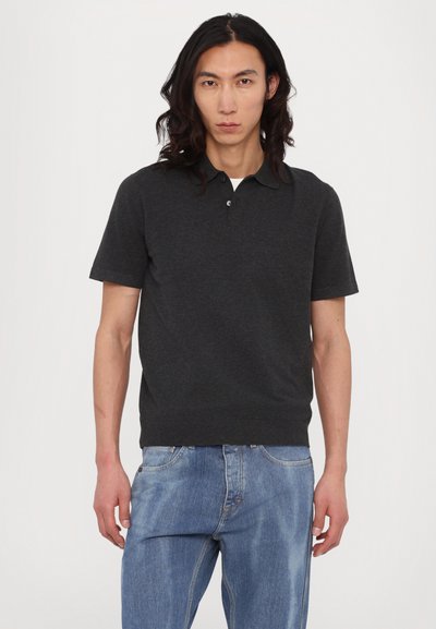 Krátky rukáv polo tričko v tmavošedej bavlny, s klasickým golierom a trojradovým zapínaním na gombíky. Spárované so svetlomodrými džínsami.