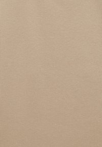 Tissu beige côtelé avec une surface texturée. Des lignes verticales créent un motif régulier sur toute la matière. Doux et extensible.