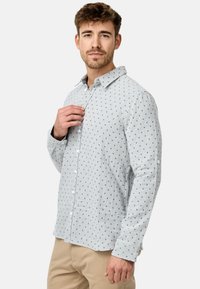 Camisa de algodón de manga larga en gris claro con un sutil patrón de cuadros en azul y marino. Presenta un cuello con botones y botones en los puños.