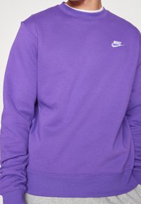 Lila sweatshirt av mjukt tyg med rund halsringning och ribbade muddar. Nike-logotyp i vitt på vänster bröst.