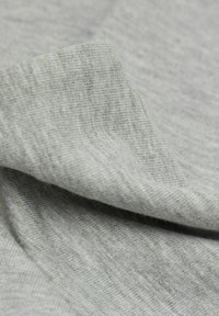 Jasnoszara tkanina o drobnej prążkowanej strukturze, fałdy ukazujące miękkość i elastyczność. Gładki i lekki materiał odpowiedni do odzieży.